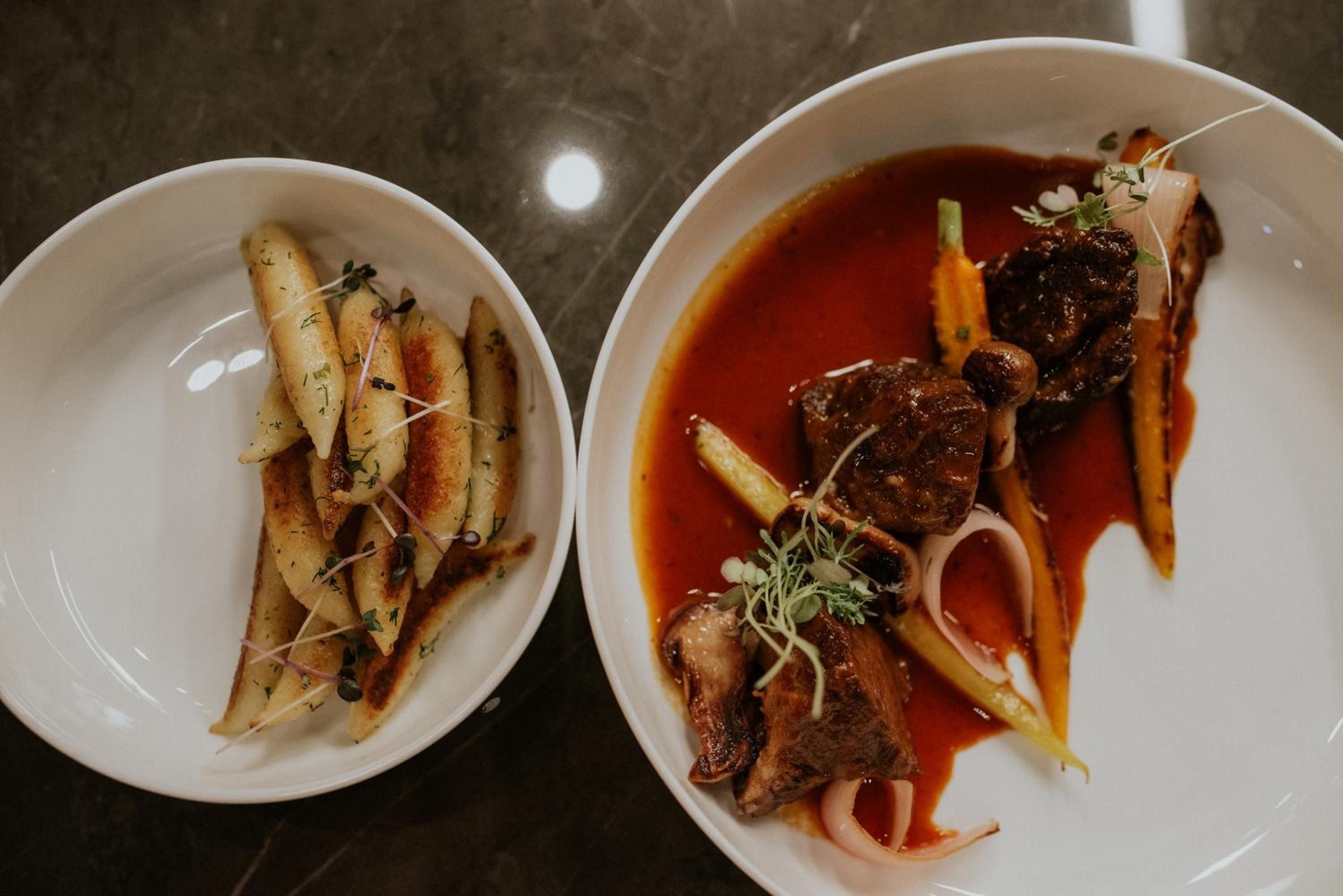 Artfully plated lamb medallions glisten in rich jus alongside herb-dusted fingerling potatoes, showcasing the culinary finesse that defines every meal at this intimate dining venue.