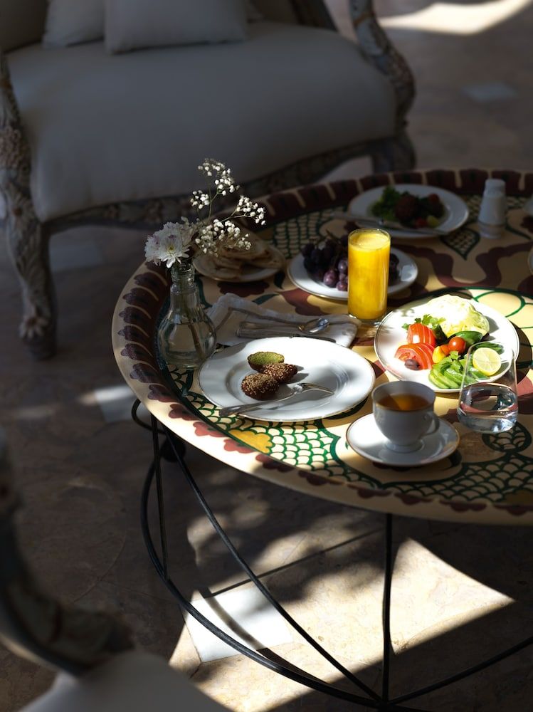 Sunlight dances across the mosaic-topped table where morning coffee mingles with fresh pastries, creating an intimate breakfast moment in this beautifully appointed Moroccan riad.