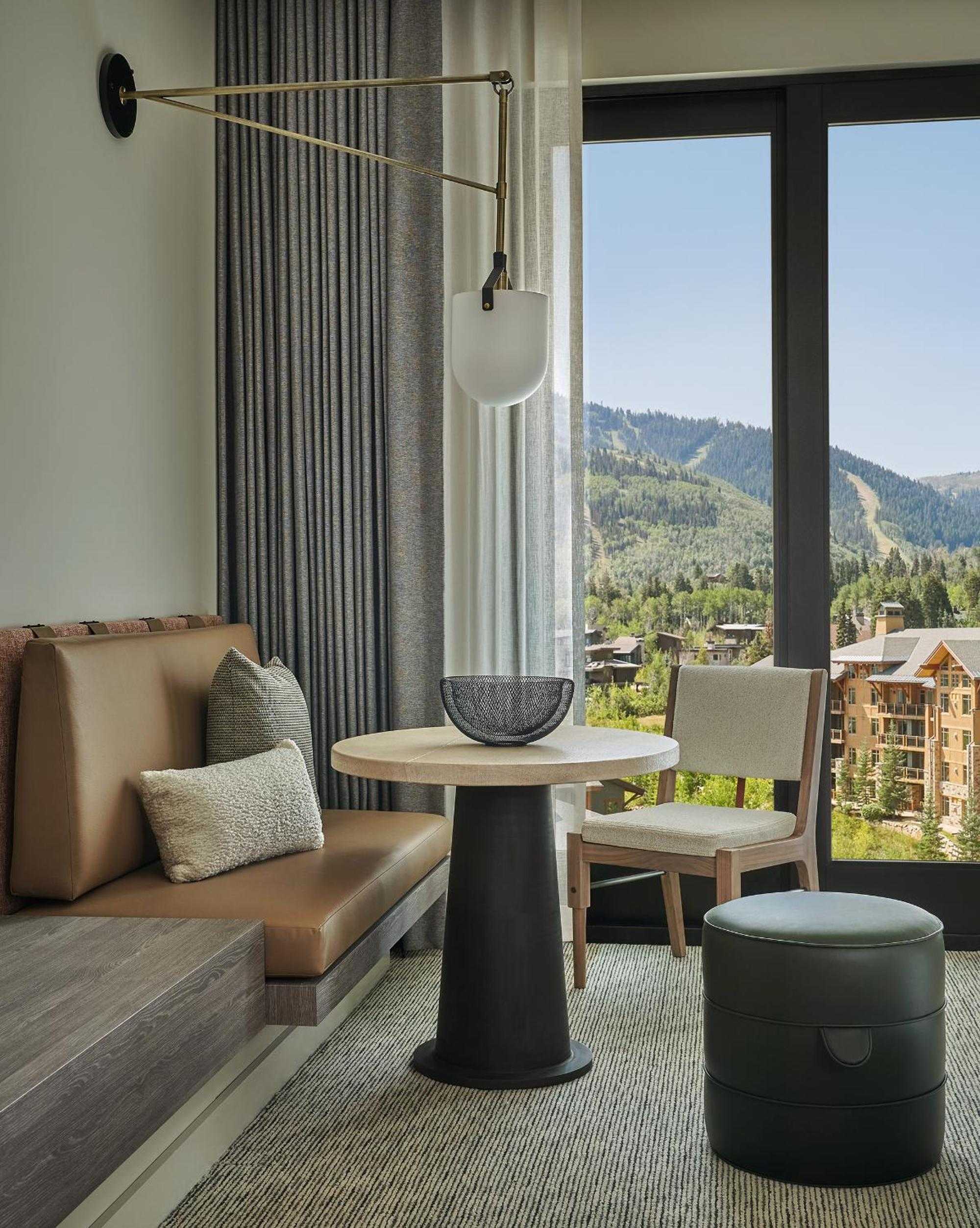 Floor-to-ceiling windows frame the Wasatch Mountains from this sophisticated suite, where brass swing-arm sconces and neutral tones create an alpine sanctuary above Park City's slopes.