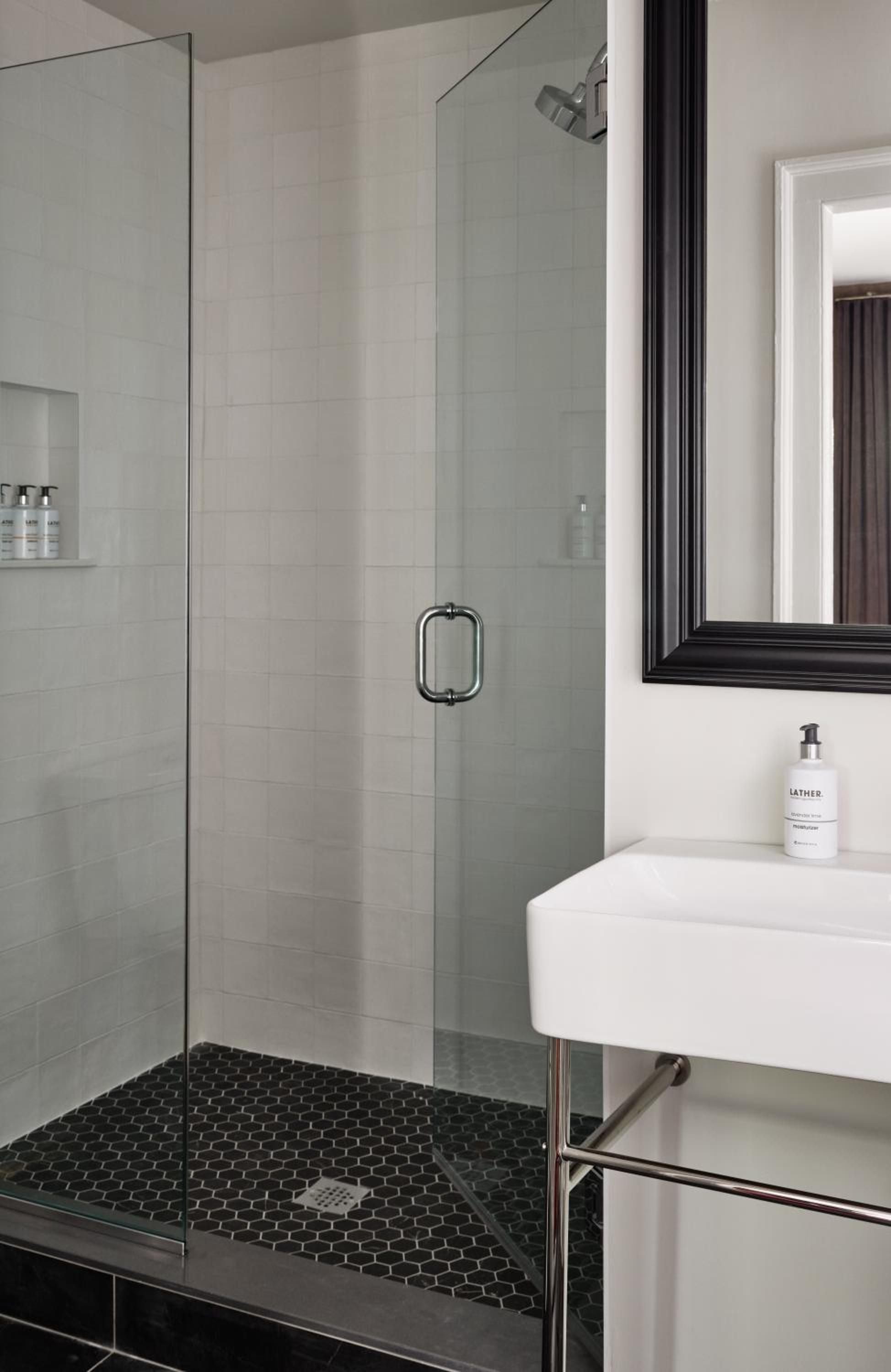 Crisp white marble meets charcoal hexagonal tiles in this spa-like retreat, where glass enclosures frame rain showers and chrome fixtures catch morning light.