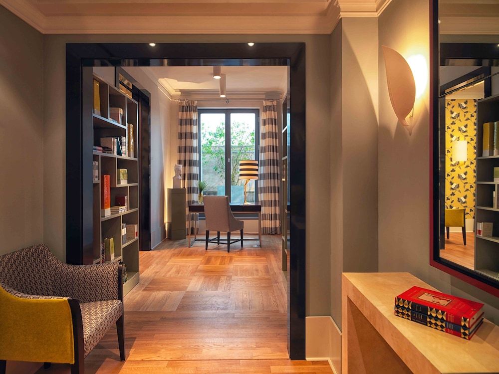 Warm wood floors guide guests through thoughtfully curated reading nooks, where striped curtains frame garden views and built-in shelves invite quiet contemplation.