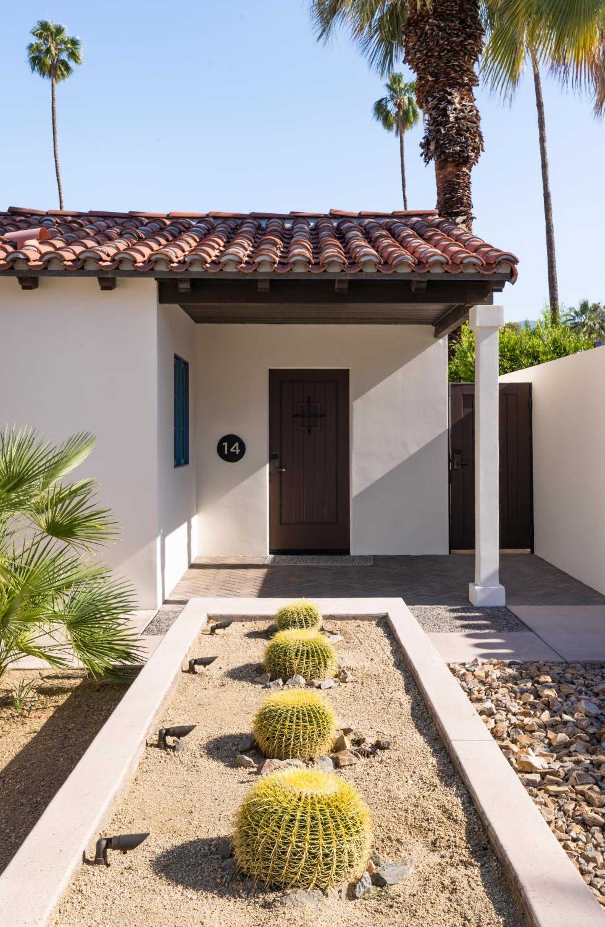 Adobe walls and terracotta tiles frame the intimate entry to Villa 14, where golden barrel cacti punctuate a zen garden of smooth river stones.