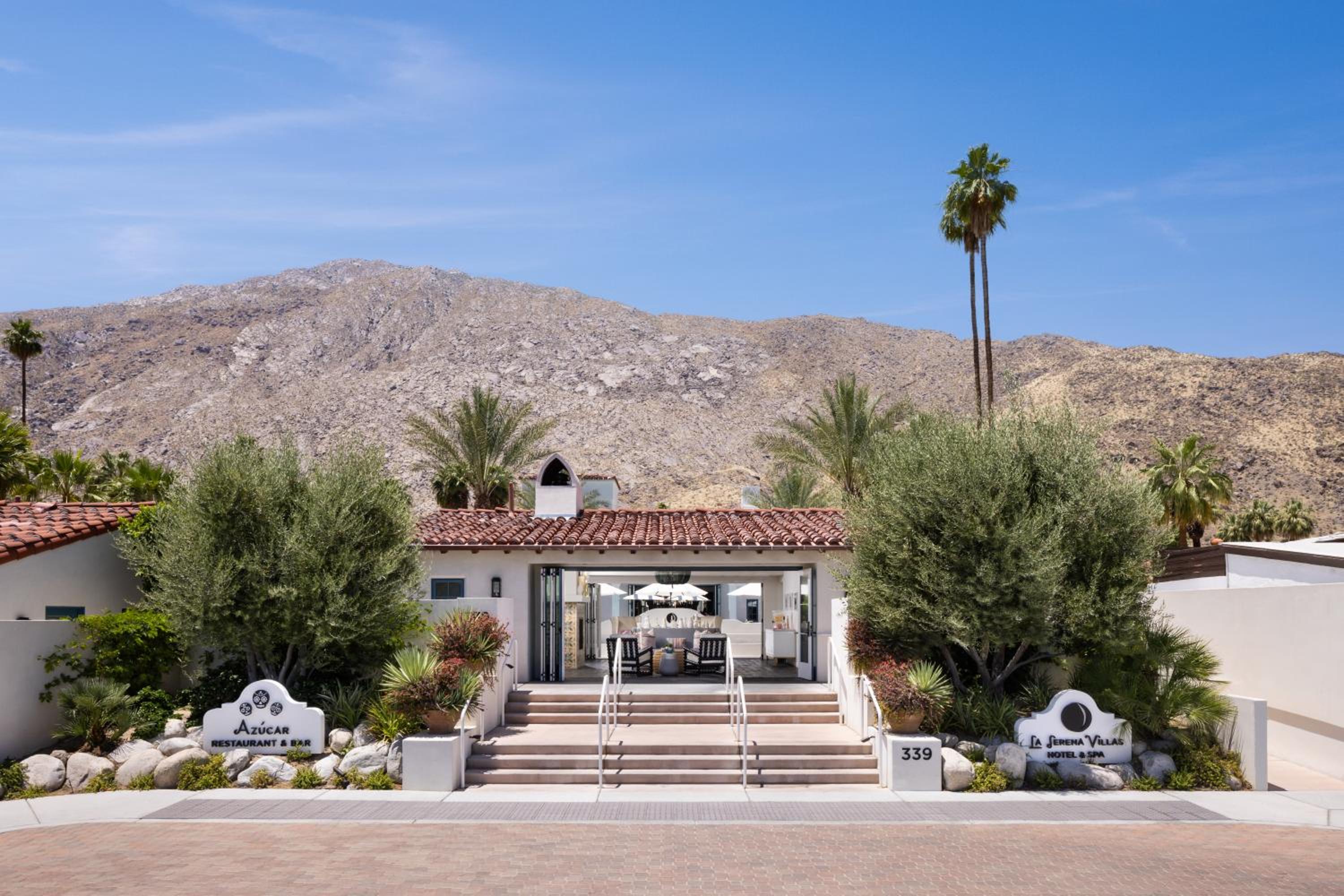 Terracotta tiles and desert palms frame the welcoming entrance, where stone steps lead to airy interiors beneath the dramatic backdrop of sun-baked mountains.