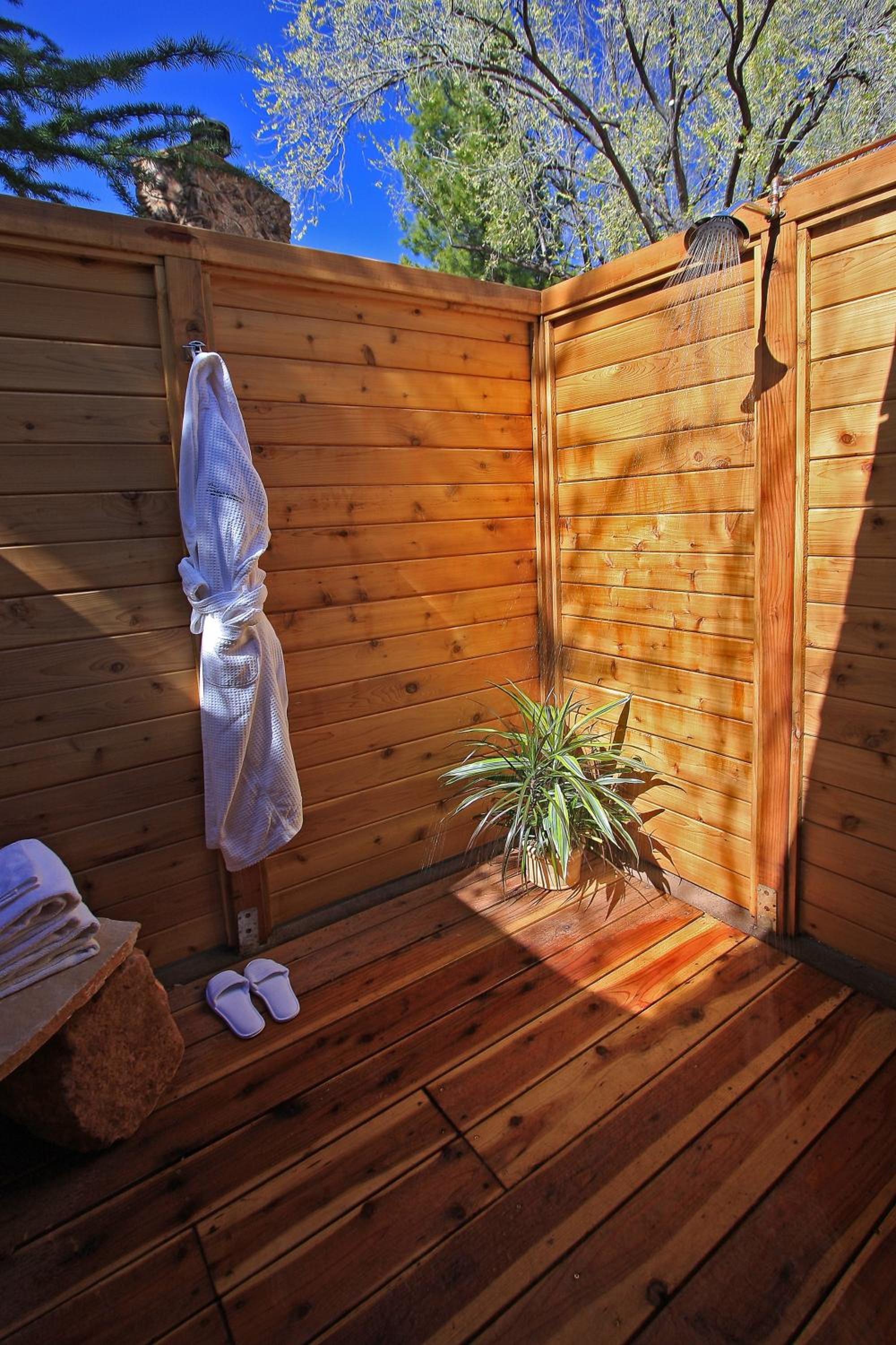 Warm cedar planks embrace this private outdoor shower sanctuary, where rainfall cascades under Arizona's impossibly blue sky amid fragrant desert air.
