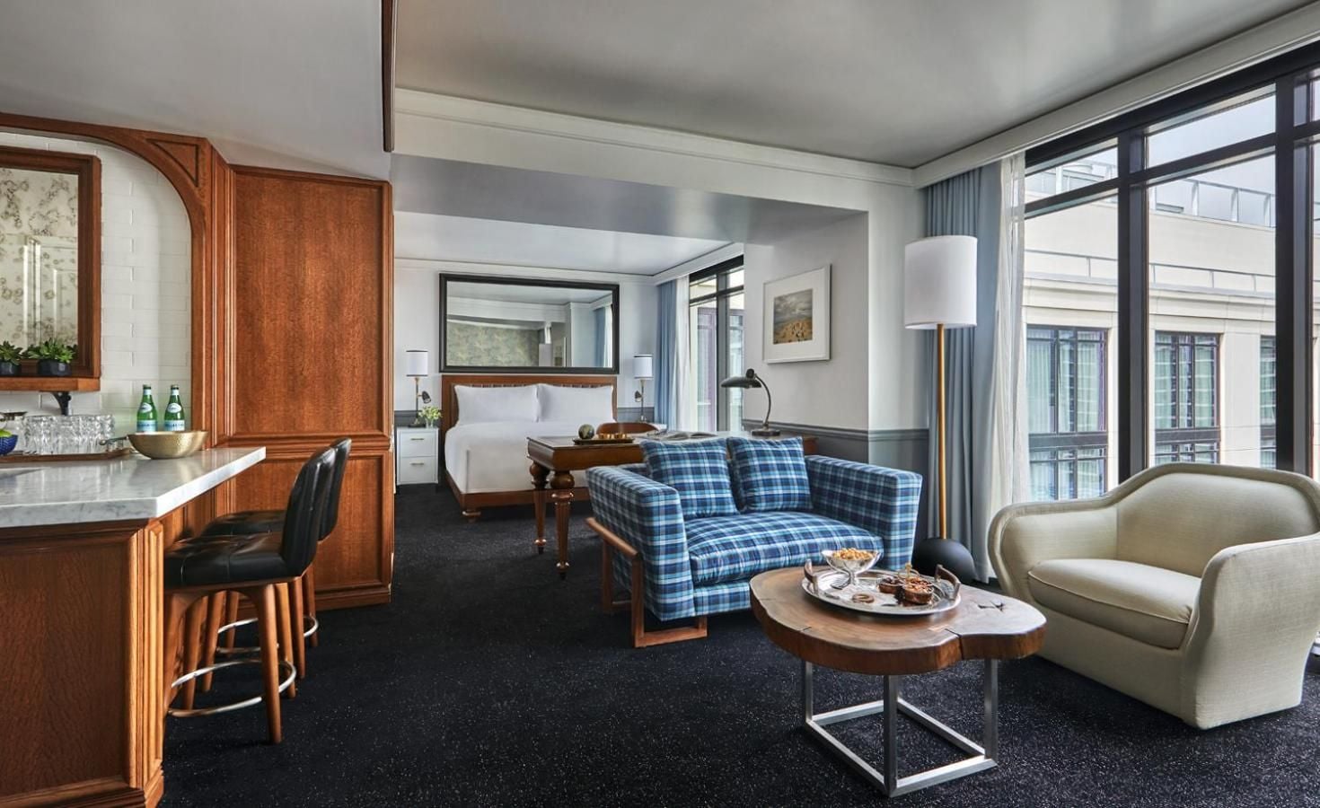 Warm wood millwork and blue tartan upholstery create an inviting residential feel in this corner suite, where floor-to-ceiling windows frame downtown San Diego's historic architecture.