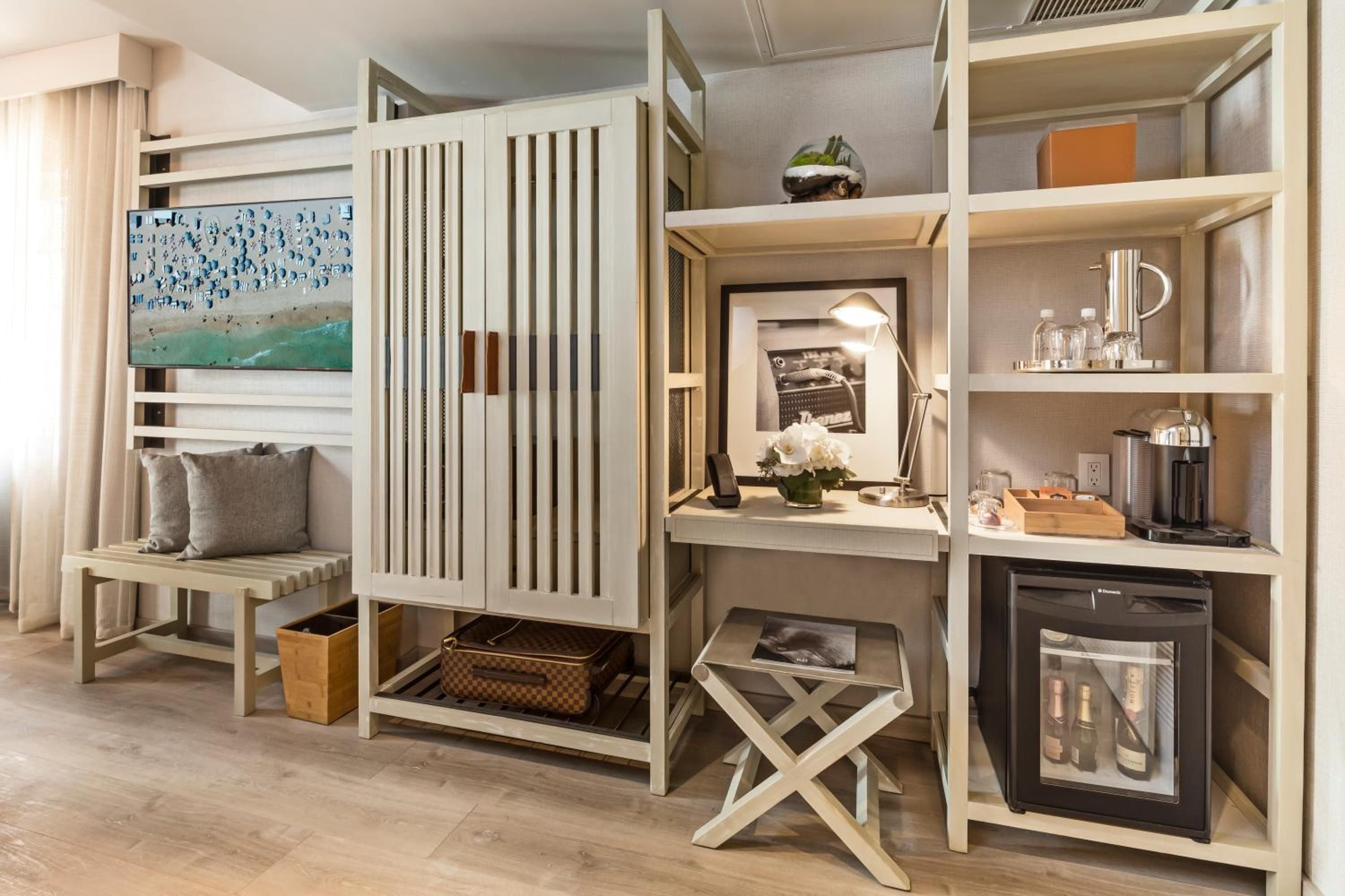 Blonde wood frameworks cleverly divide space in this compact suite, where a built-in desk nook and mini-bar create distinct zones within an airy, Scandinavian-inspired design.