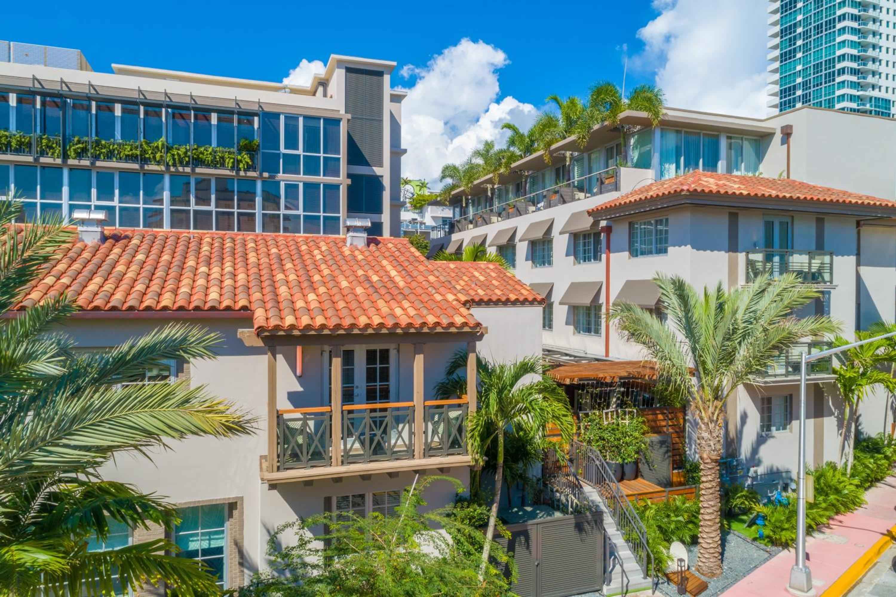 Terracotta tiles and wooden balconies create intimate Mediterranean charm against Miami's gleaming skyline, where palm fronds dance in ocean breezes.