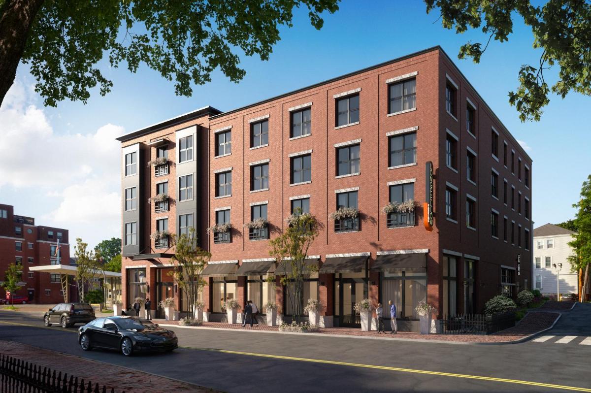 Red brick facade and street-level retail create an inviting urban presence, where tree-lined sidewalks and welcoming storefronts blend seamlessly into the neighborhood fabric.