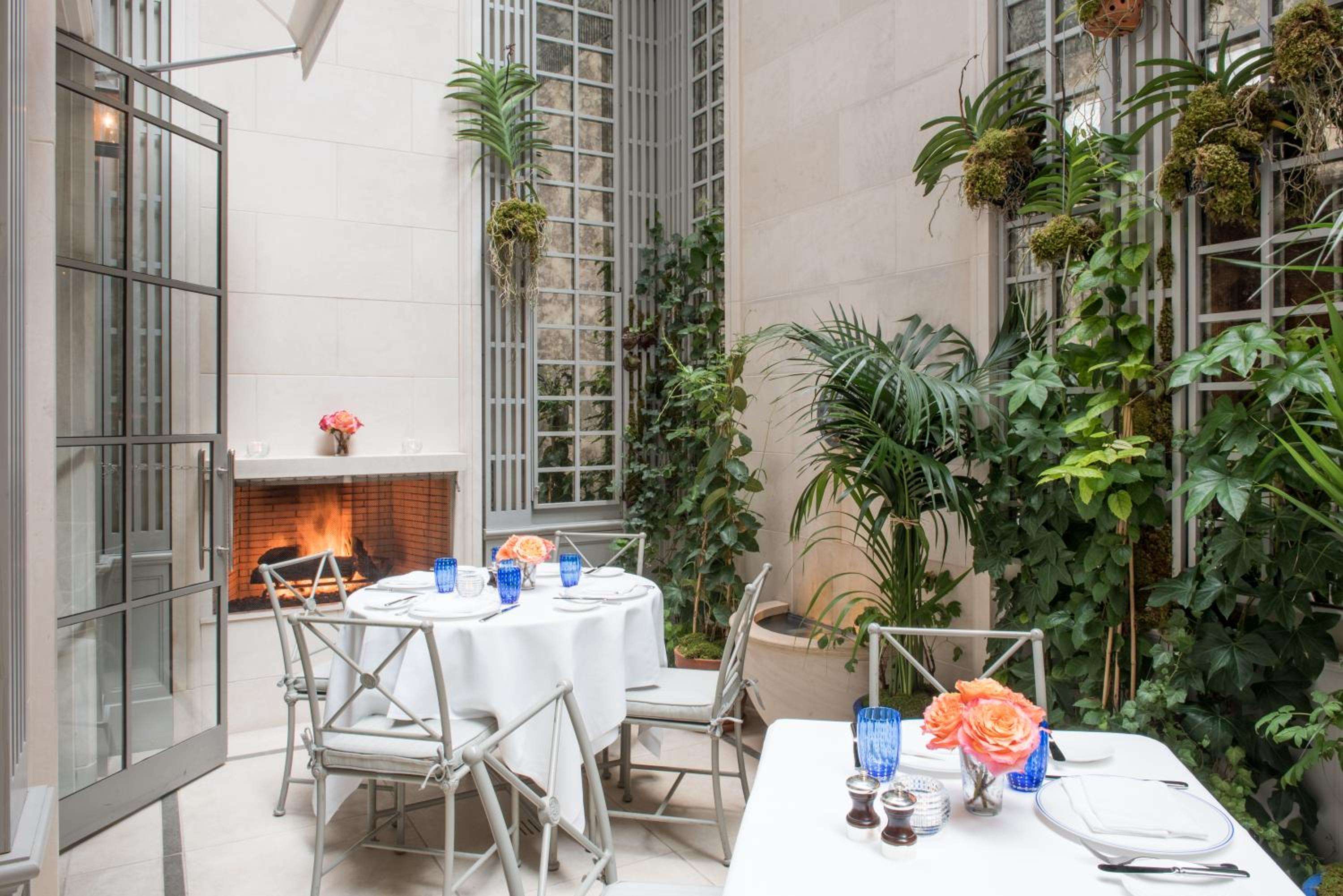 Intimate tables nestle beside a crackling fireplace in the hotel's enchanting courtyard restaurant, where climbing vines and coral-hued roses create an urban oasis.