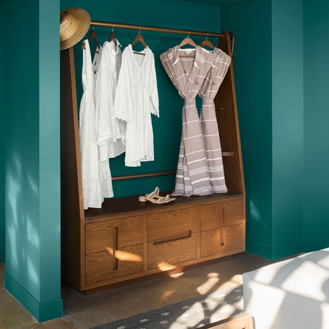Warm wood closet storage meets resort-ready robes in aquamarine-walled suites, where thoughtful design details create an intimate, boutique atmosphere bathed in golden afternoon light.