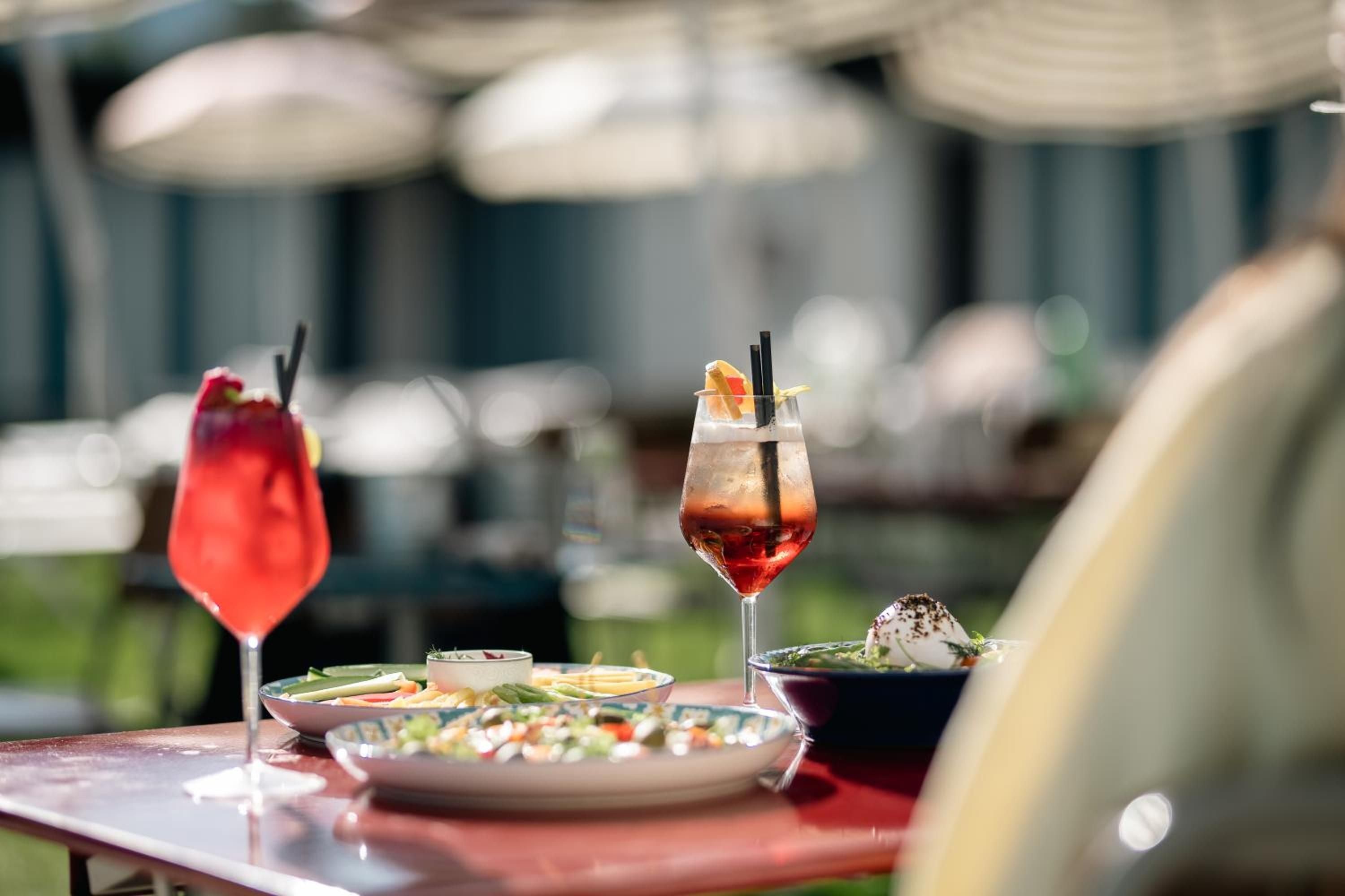 Colorful aperitifs and artfully plated dishes catch golden light on the terrace, where Alpine dining becomes an elegant affair of craft cocktails and refined mountain cuisine.