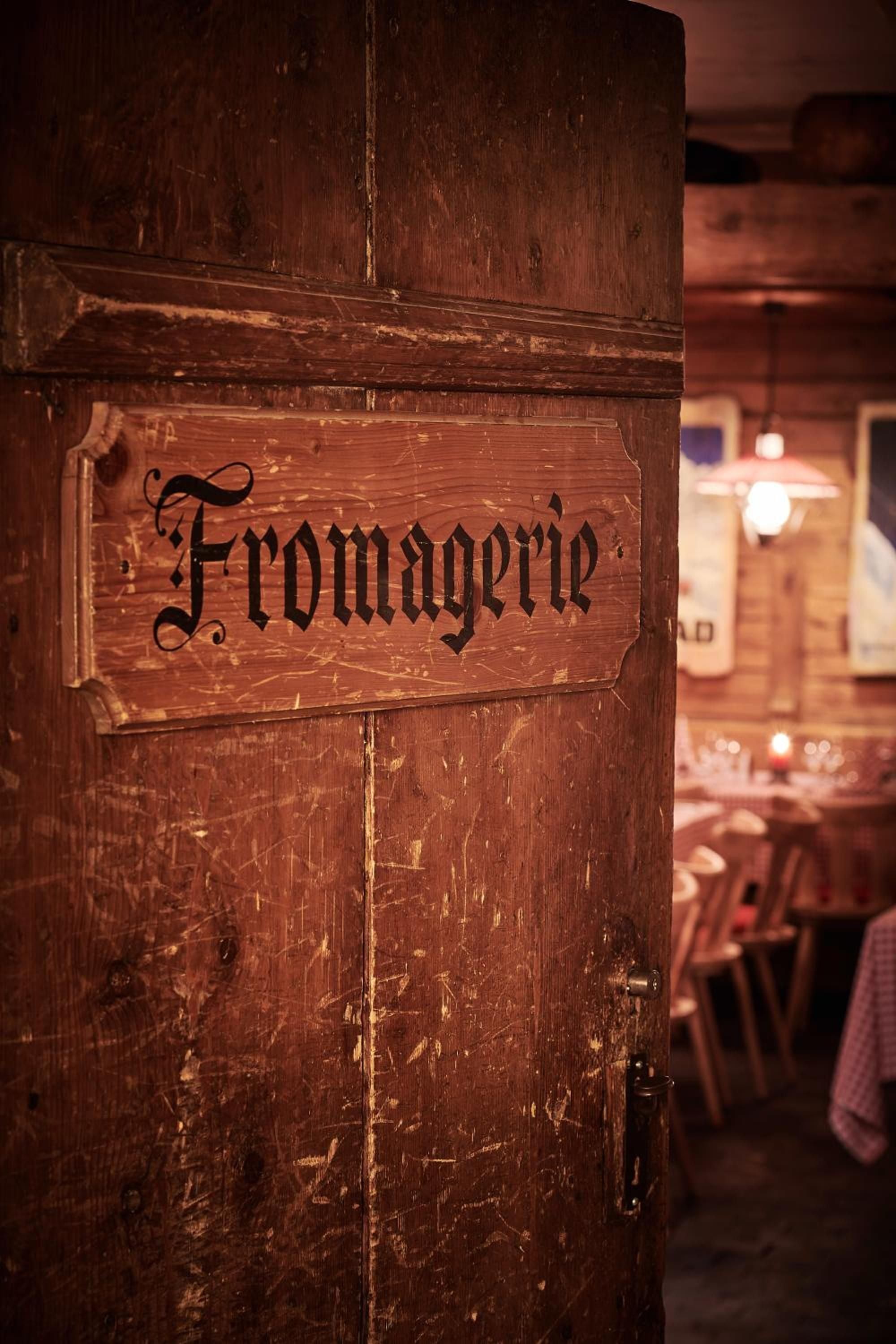 Weathered wood and Gothic lettering mark the fromagerie in this alpine restaurant, where crackling fires and centuries-old beams create an authentically rustic Swiss dining atmosphere.