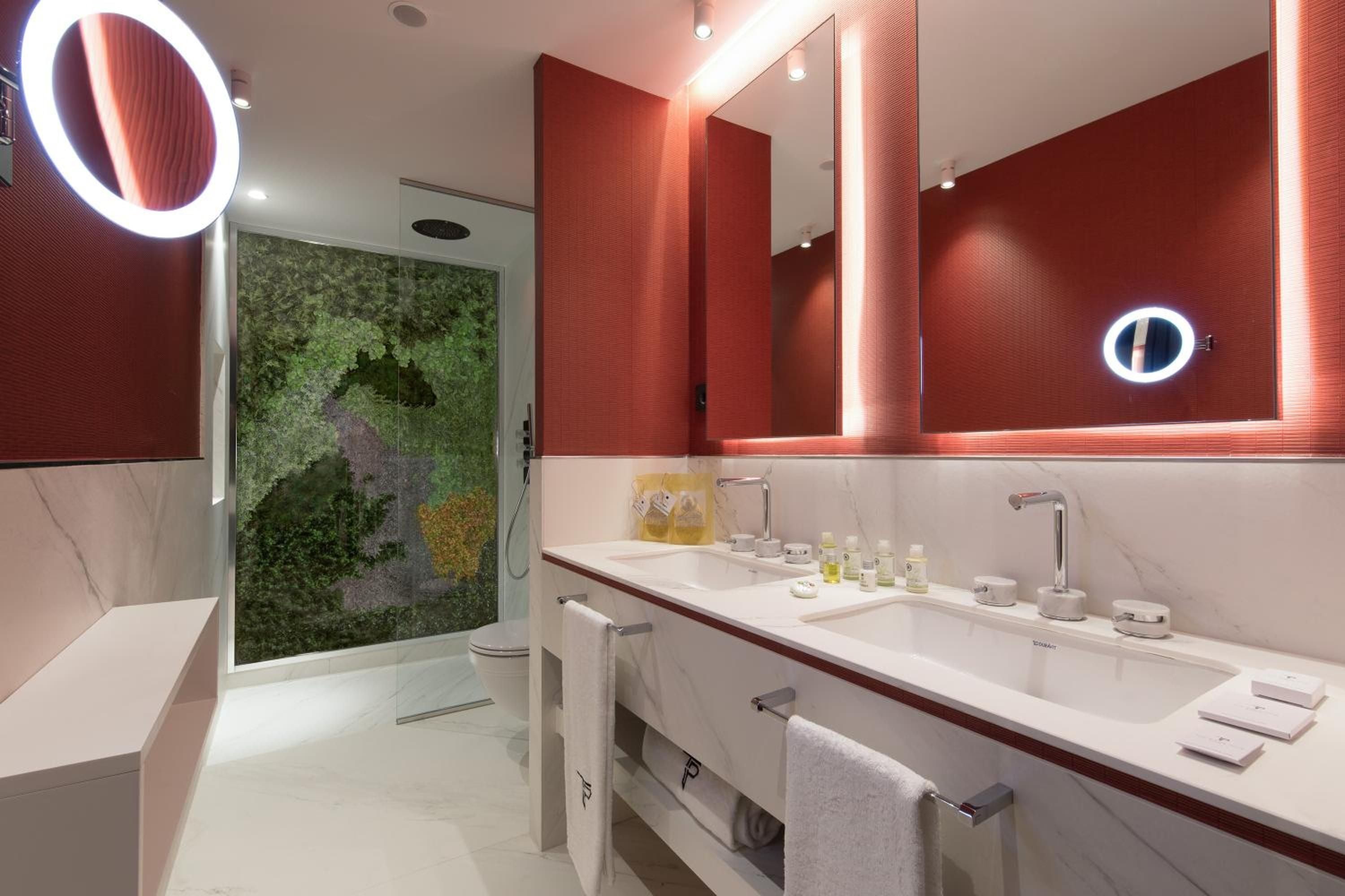 Warm terracotta walls create an intimate cocoon in the master bath, where modern fixtures meet a living moss wall that brings nature indoors.