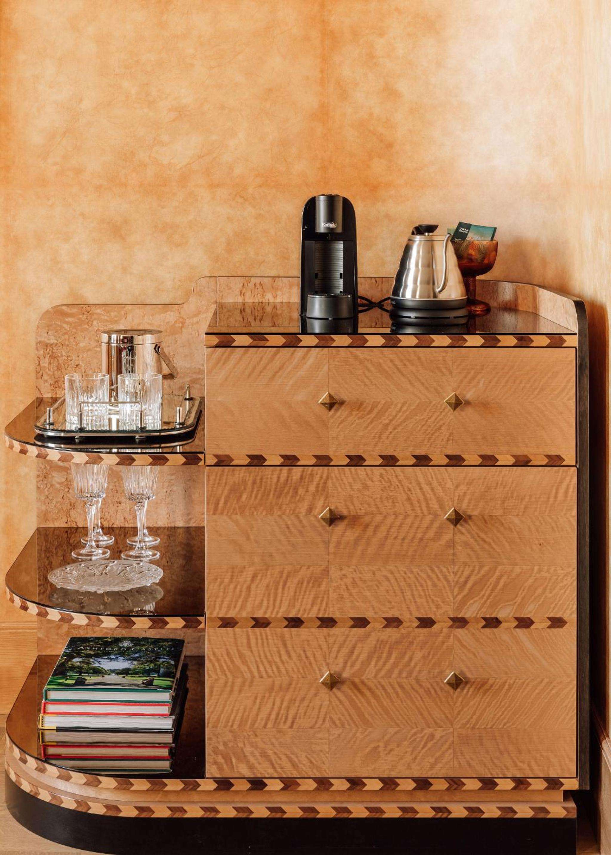 Geometric marquetry and warm wood grains create an artful drinks station, where crystal decanters catch afternoon light filtering across hand-crafted surfaces.