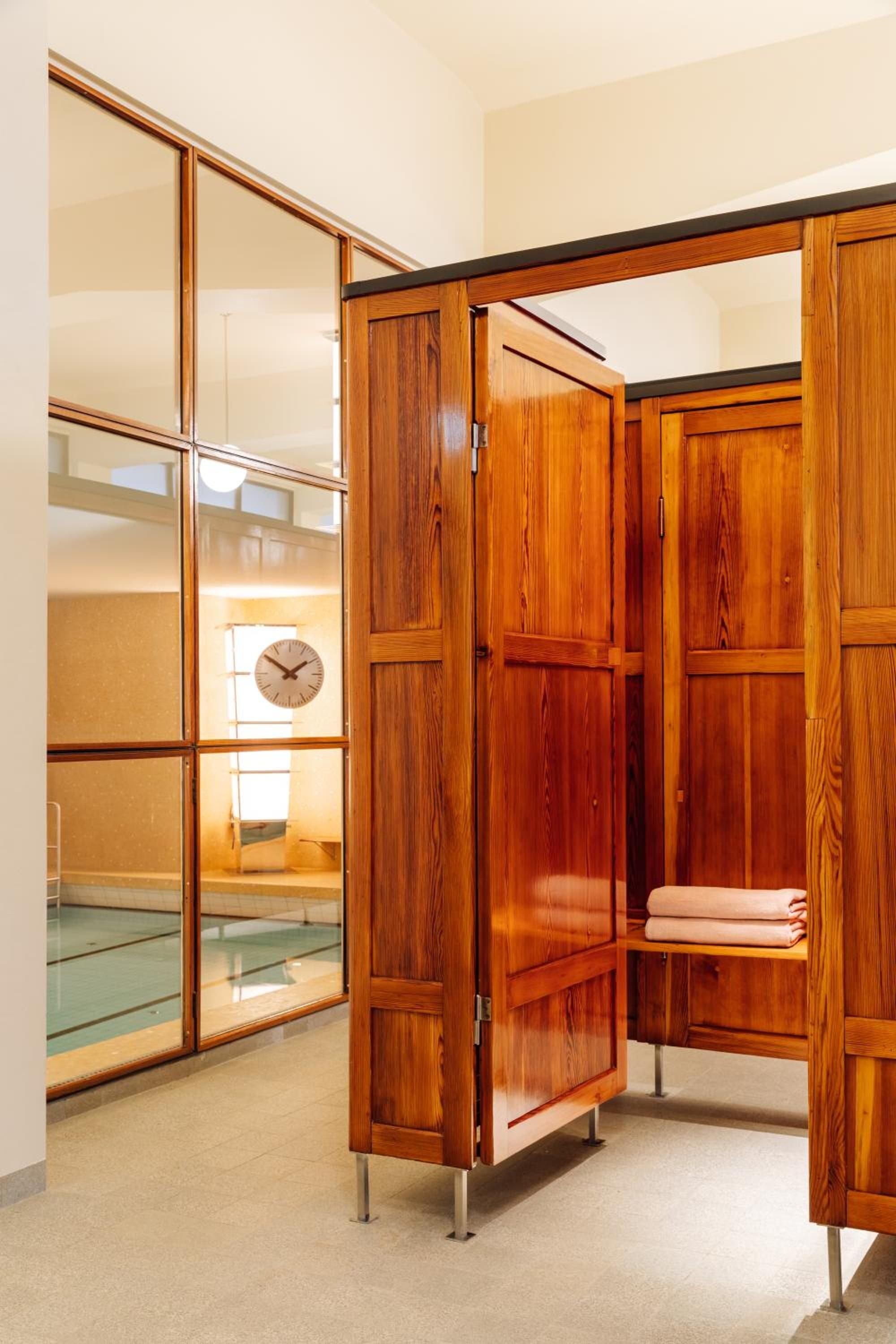 Rich teak cabinetry opens to reveal thoughtfully curated linens, while floor-to-ceiling mirrors amplify natural light in this masterfully crafted dressing area.