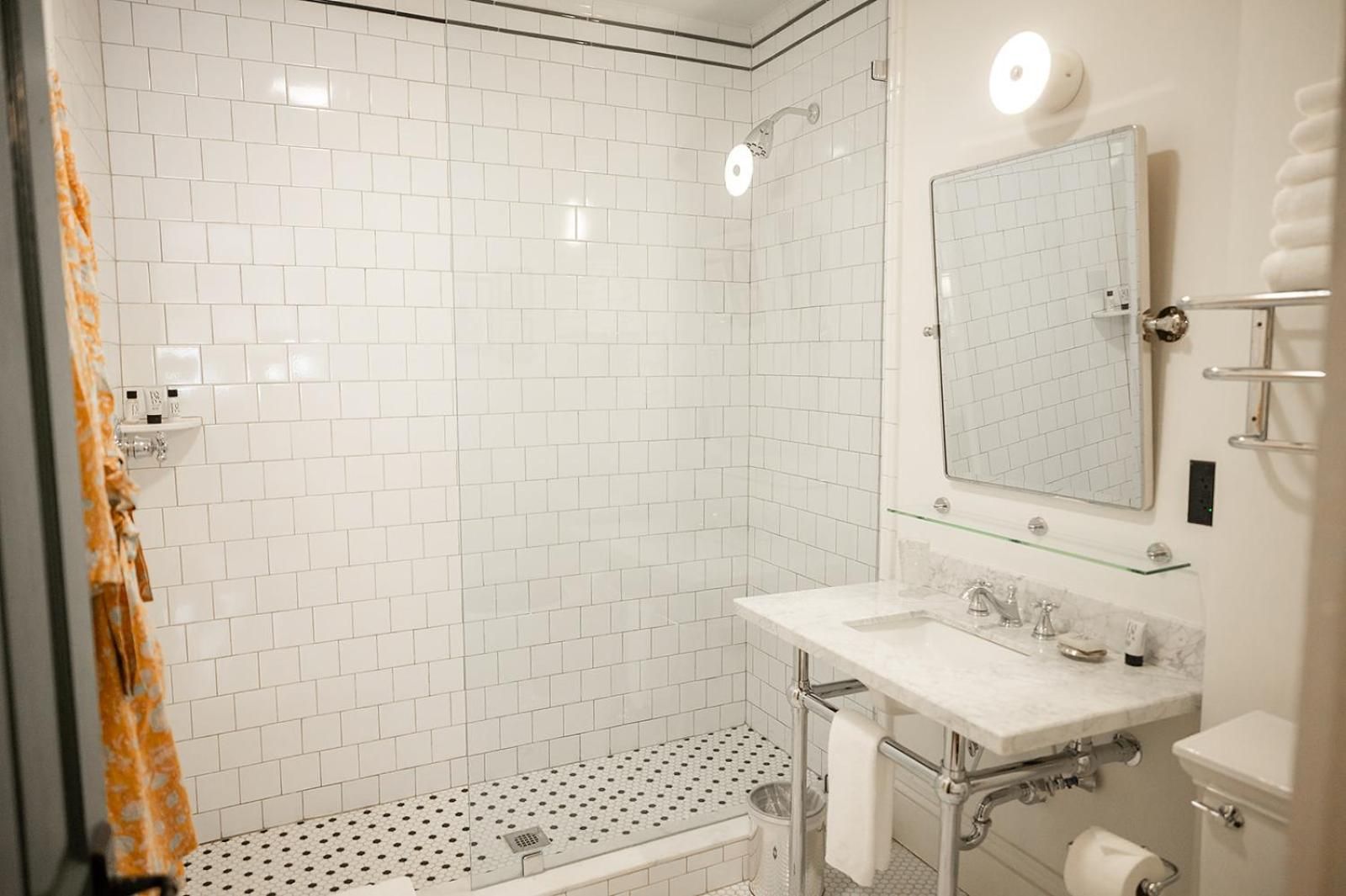 Classic subway tiles and penny floor mosaics create timeless elegance in guest bathrooms, where rainfall showers and marble vanities blend vintage charm with modern comfort.
