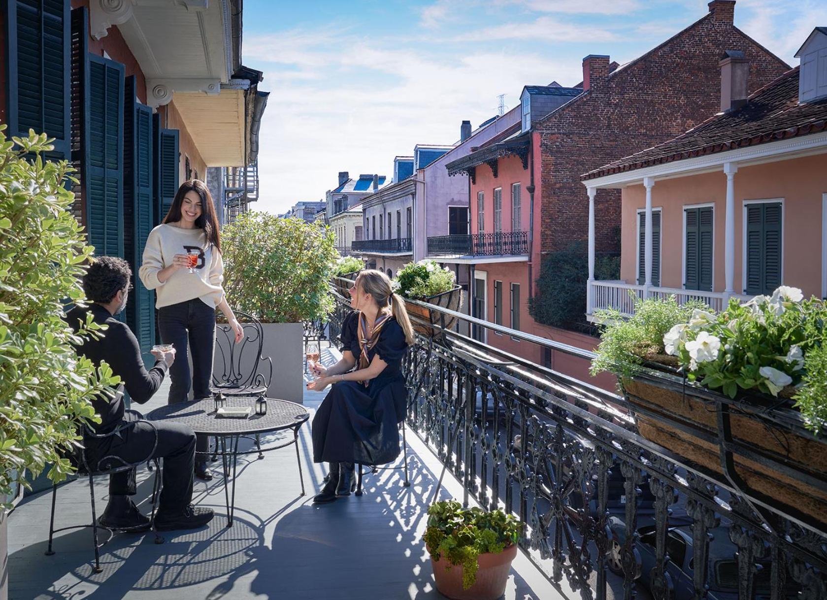 Wrought-iron balconies frame intimate moments above the French Quarter, where morning coffee mingles with historic charm and colorful Creole architecture stretches toward distant spires.