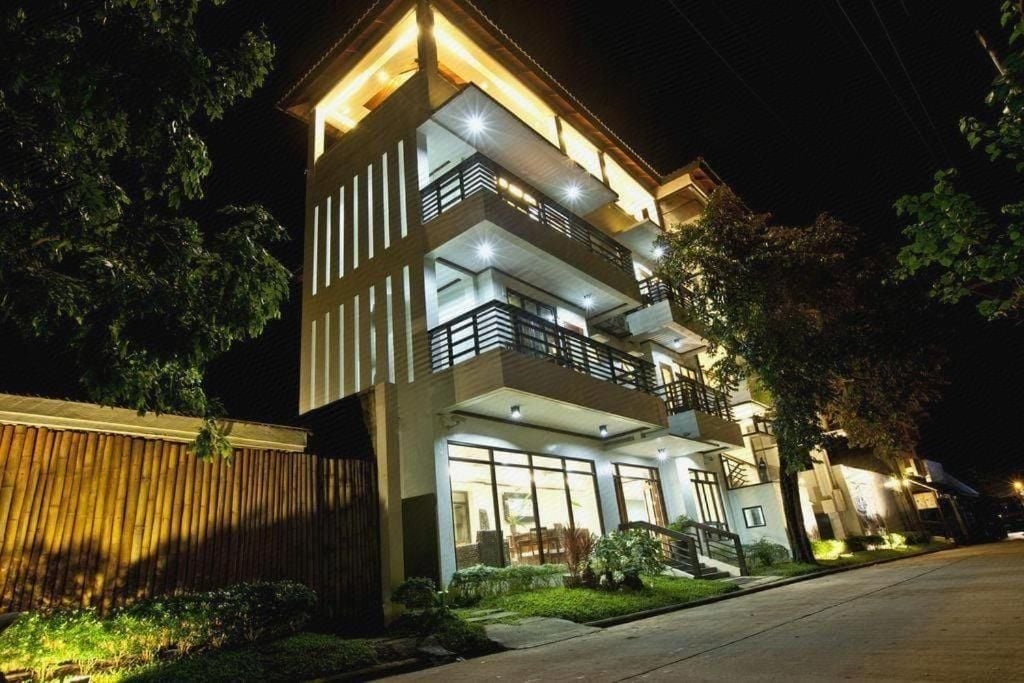 Warm golden light spills from bamboo-accented balconies into the tropical night, where modern architecture meets Filipino craftsmanship in this intimate boutique retreat.