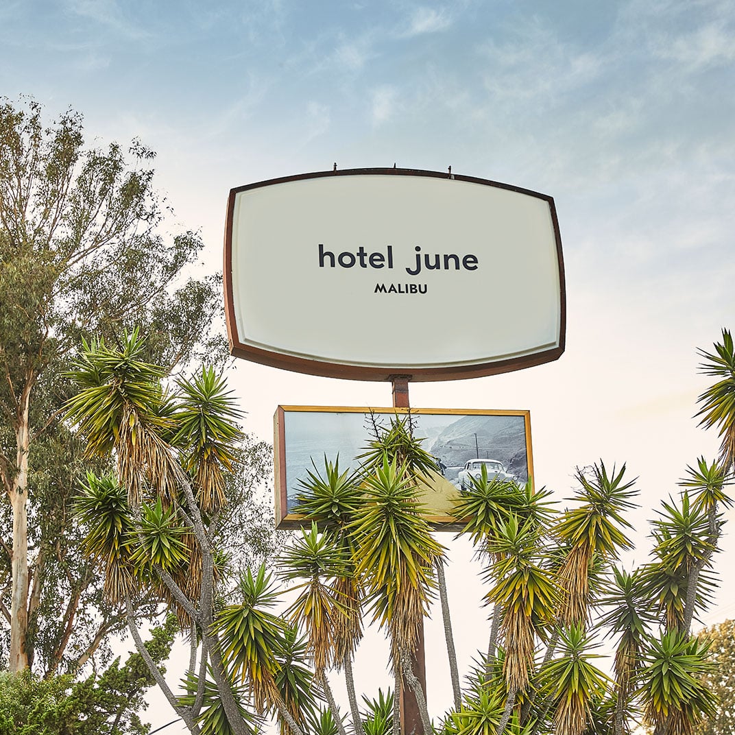 Mid-century signage rises above desert palms, announcing this Malibu retreat where vintage California charm meets contemporary coastal sophistication along the iconic Pacific Coast Highway.