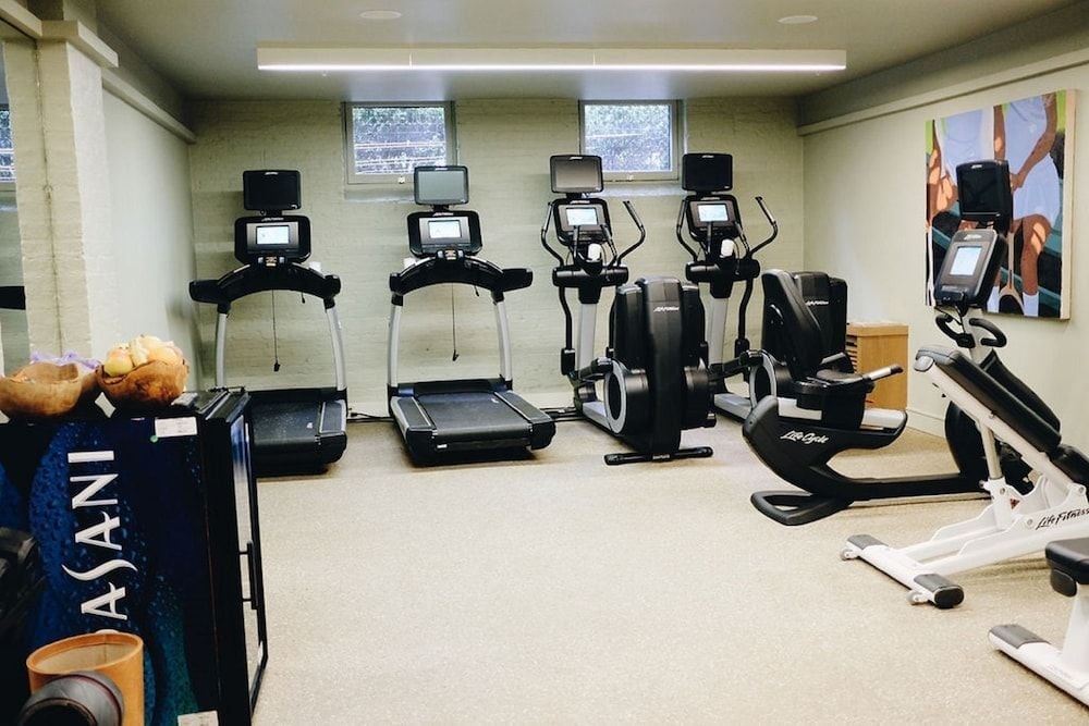 State-of-the-art cardio equipment lines the sleek fitness center, where floor-to-ceiling windows bathe modern treadmills and ellipticals in natural light.
