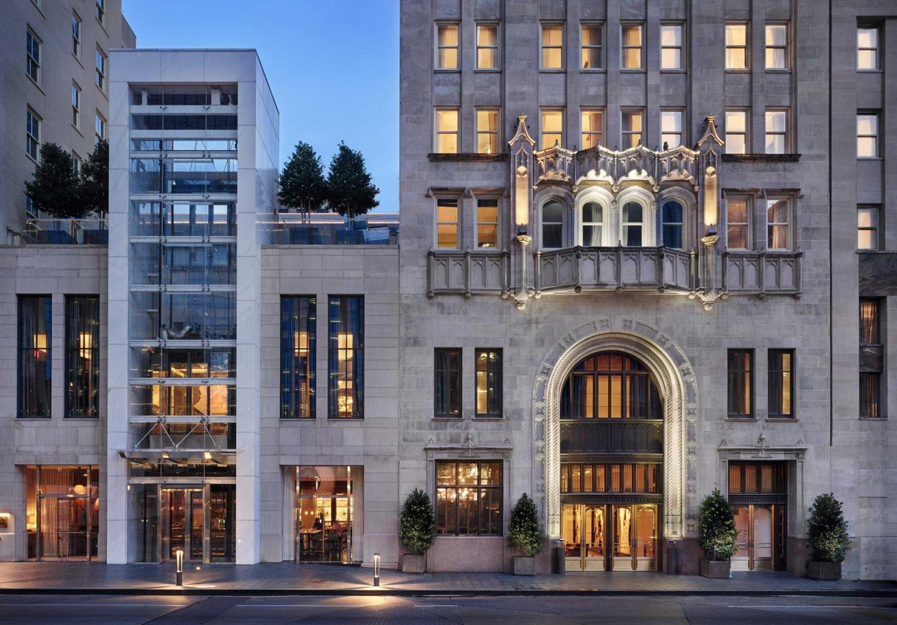Gothic Revival grandeur meets modern sophistication as warm light spills from arched windows onto the limestone facade, while the illuminated ornate balcony creates an enchanting twilight welcome.