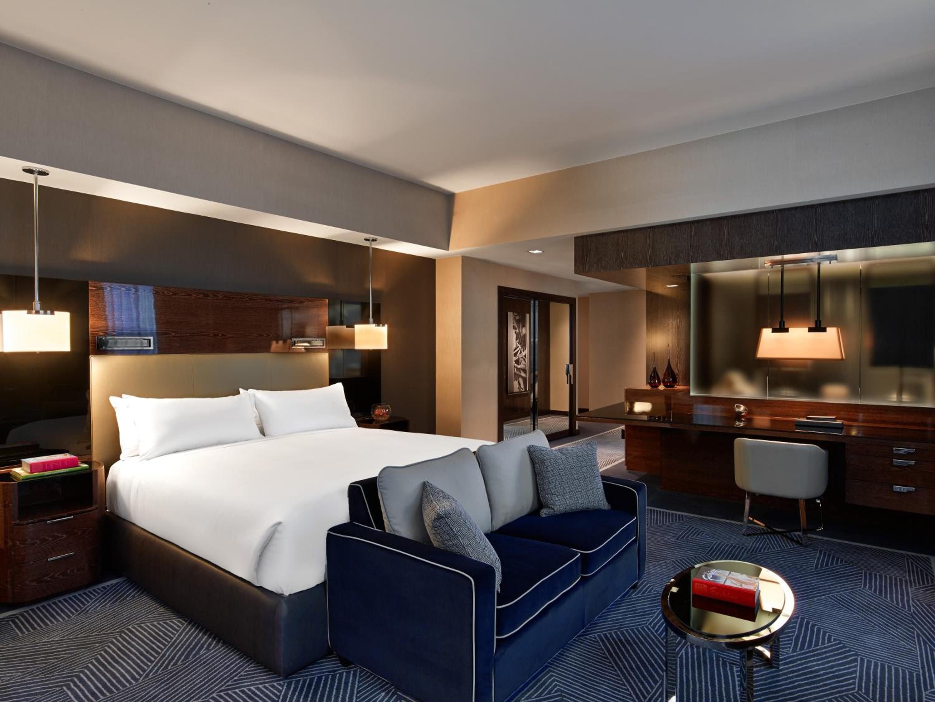 Warm pendant lights cast a honeyed glow over rich walnut surfaces and navy velvet seating, creating an intimate sanctuary where modern luxury meets residential comfort.