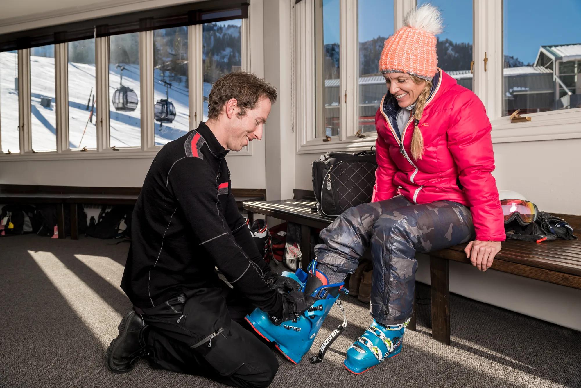 Expert boot fitters ensure perfect ski equipment setup in the lodge's warm interior, where mountain light streams through windows overlooking snowy slopes and gondola lines.