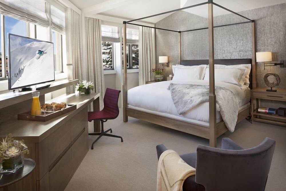 Four-poster beds and mountain views define these sophisticated guest quarters, where warm wood tones and crisp linens create an inviting alpine retreat.