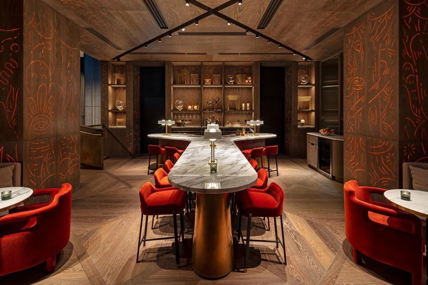 Rich walnut paneling adorned with amber-hued murals creates an intimate speakeasy atmosphere, where plush crimson velvet chairs beckon around marble-topped tables beneath dramatic exposed beams.