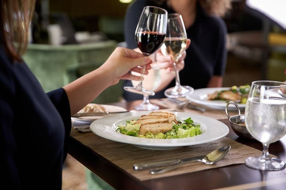 Hands raise crystal glasses in celebration as grilled Caesar salad arrives at tableside, the intimate dining room buzzing with warm conversation and clinking stemware.