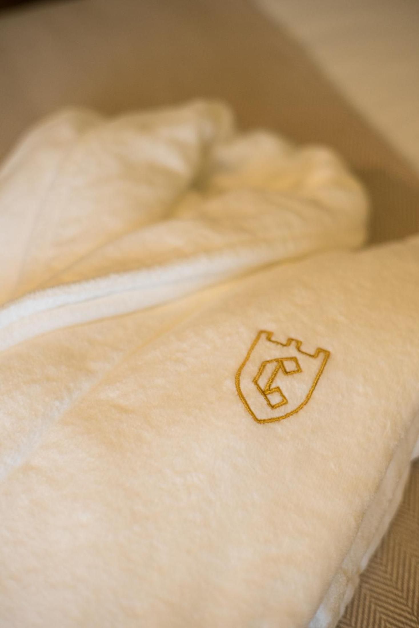 Crisp white linens bear the hotel's golden crest, a subtle reminder of regal heritage in every carefully appointed guest room at this Porto palace.
