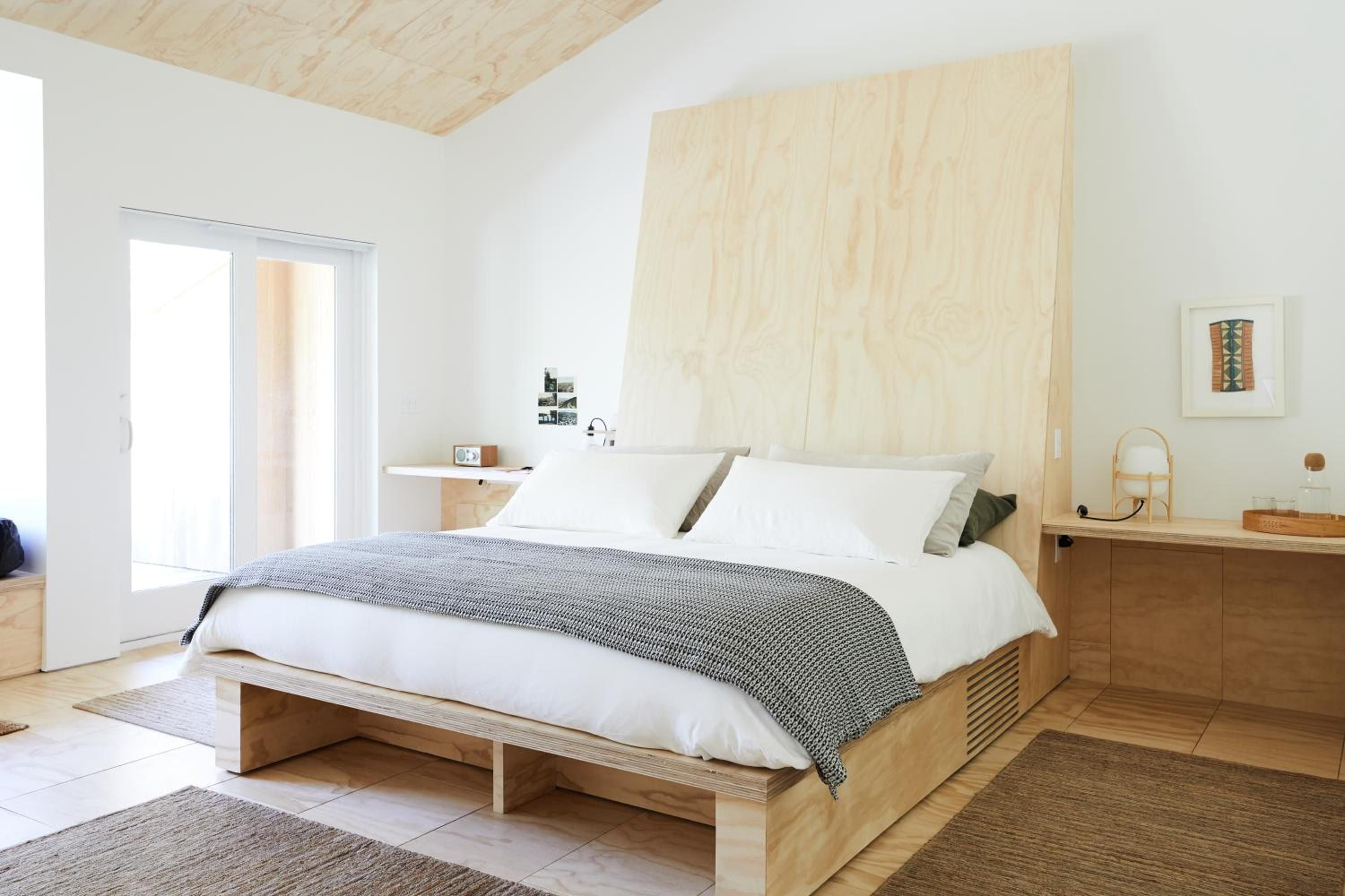 Light-washed wood and crisp white linens create a serene sanctuary, where exposed ceiling beams and minimalist furnishings blur the line between rustic and refined.