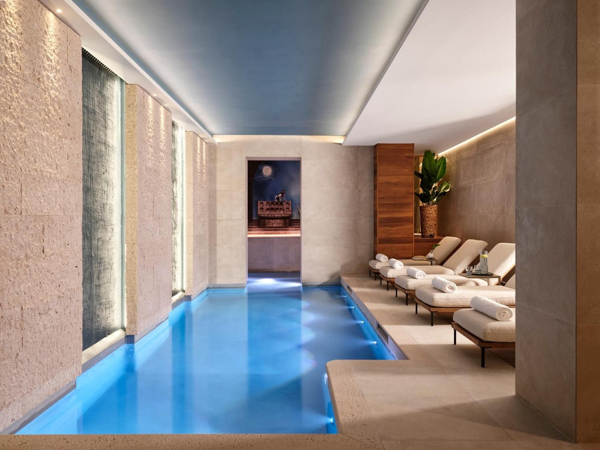 Ethereal blue light dances across travertine walls in this subterranean sanctuary, where plush loungers invite lingering moments between thermal pool sessions.