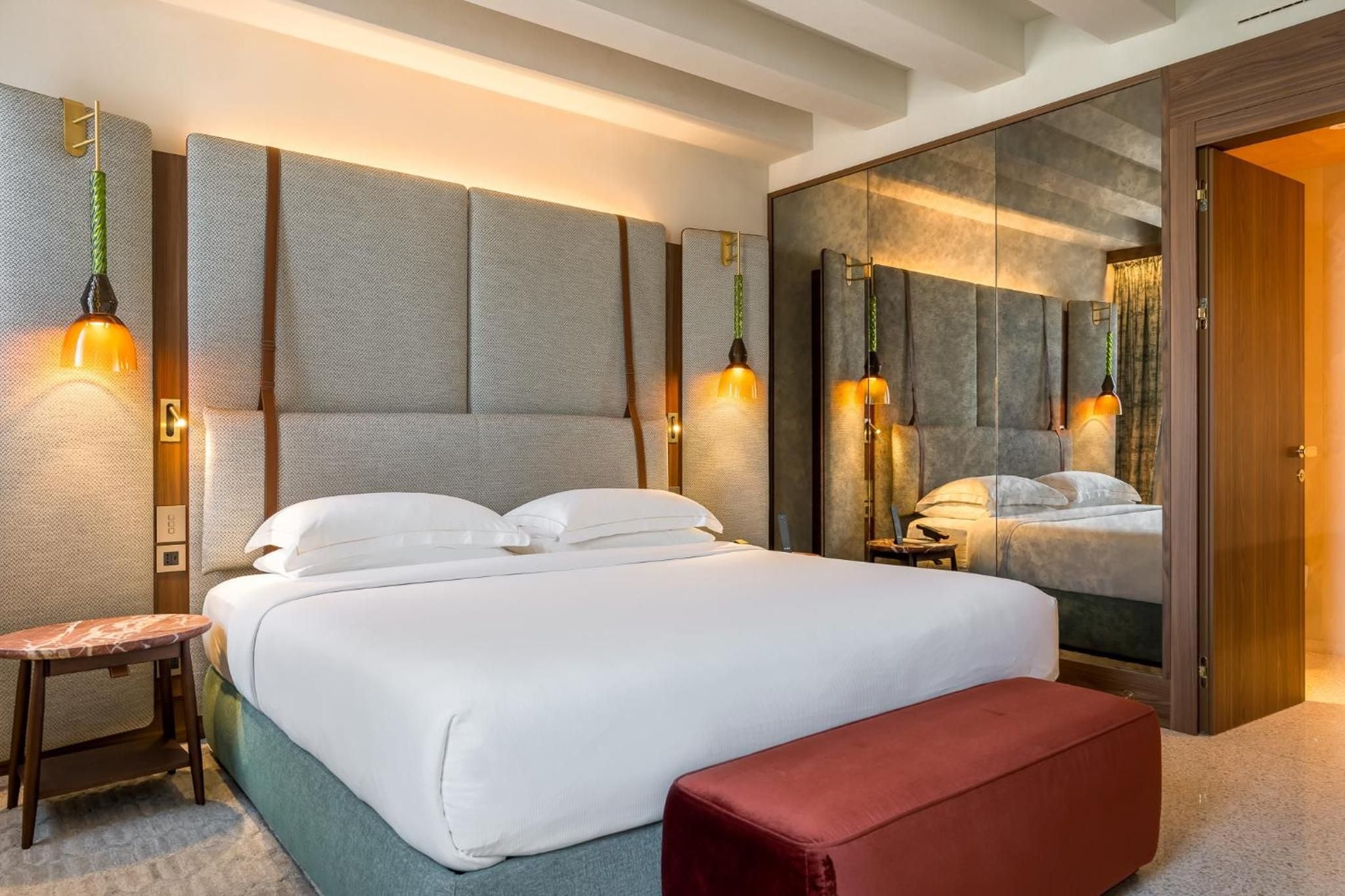 Amber pendant lights cast honeyed glows above the plush headboard, while mirrored wardrobes double the intimate warmth of this thoughtfully appointed guest room.