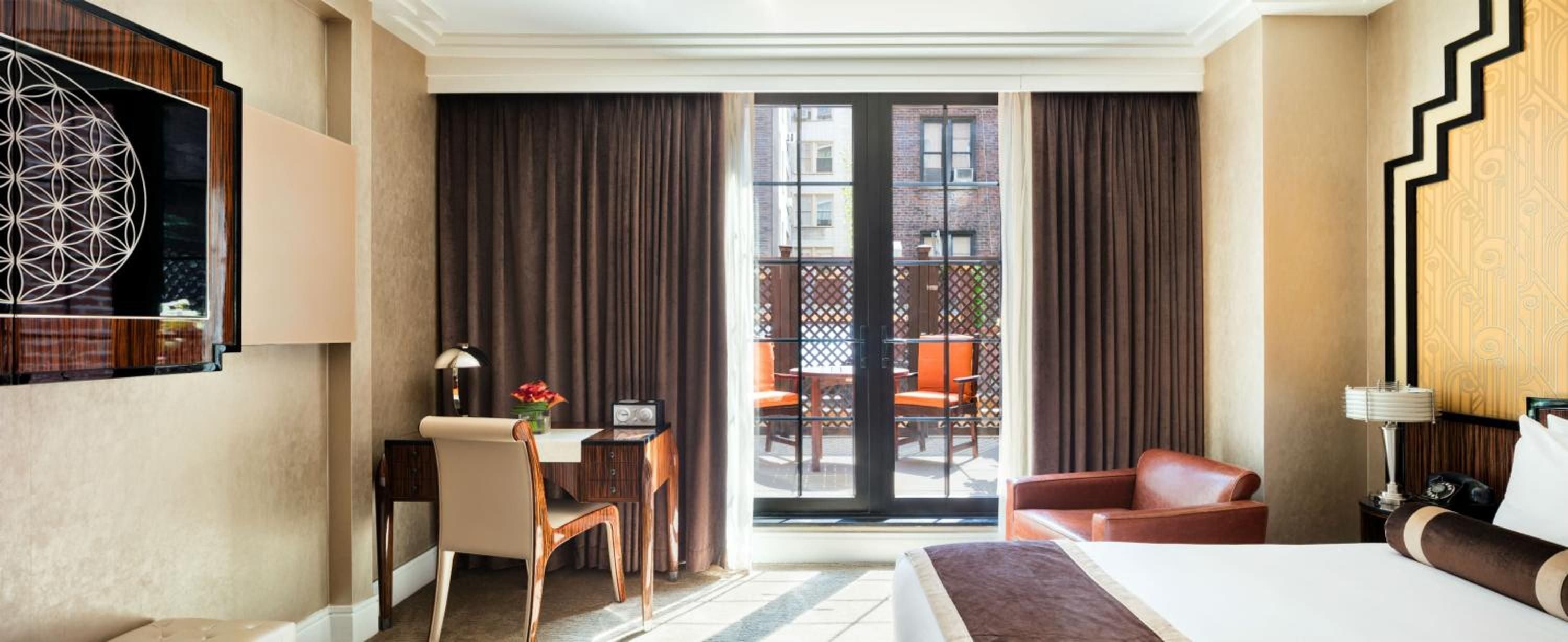 Rich walnut furnishings and geometric artwork create sophisticated warmth in guest rooms, where sliding doors open to private terraces overlooking Greenwich Village's charming brick facades.
