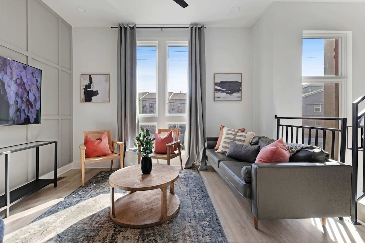 Stylish living room featuring a wall-mounted smart TV, a sleek leather couch, a modern coffee table, and three elegant accent chairs for a cozy and inviting ambiance.