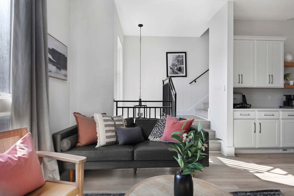 Stylish living room featuring a wall-mounted smart TV, a sleek leather couch, a modern coffee table, and three elegant accent chairs for a cozy and inviting ambiance.