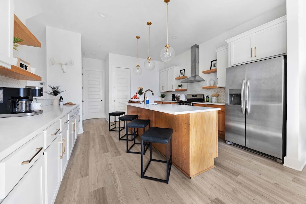 Fully equipped kitchen with a spacious pantry and a large island with five barstools, perfect for meal prep and casual dining.