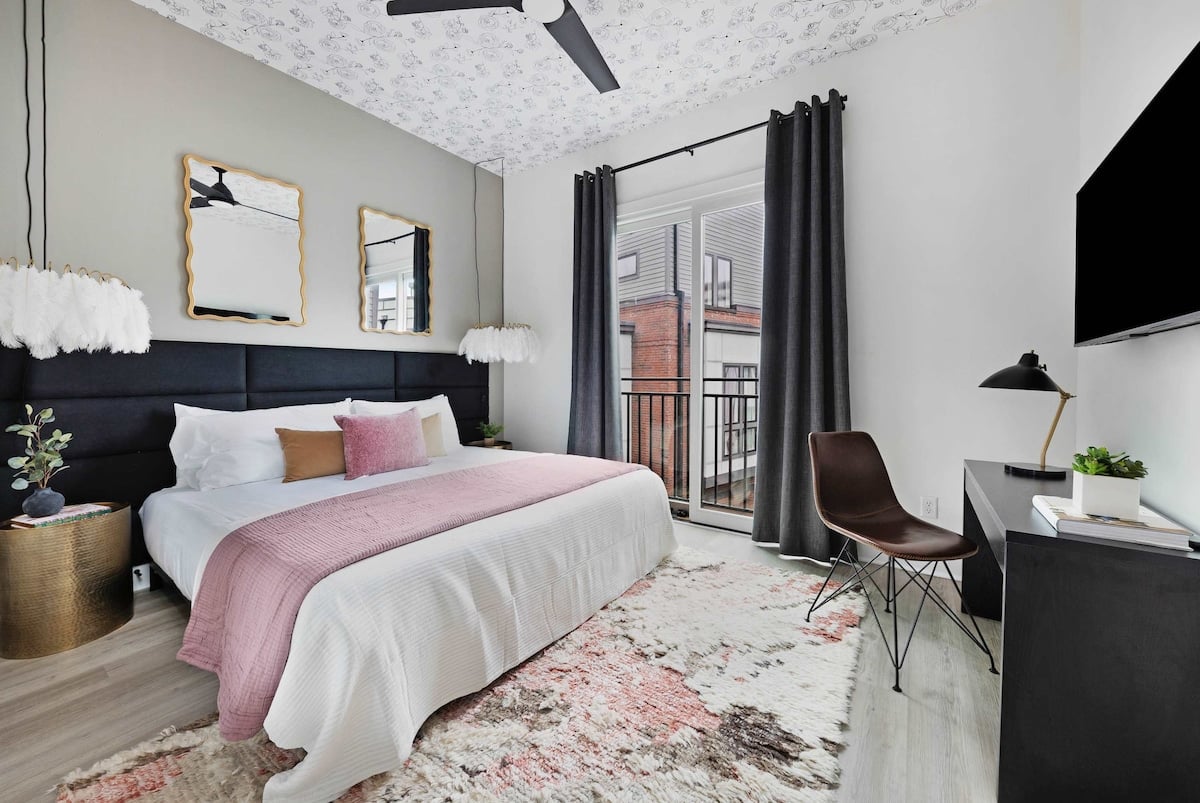 Elegant bedroom with a king bed, walk-in closet, and a private balcony featuring two chairs. The en-suite bathroom includes a modern shower for your comfort.