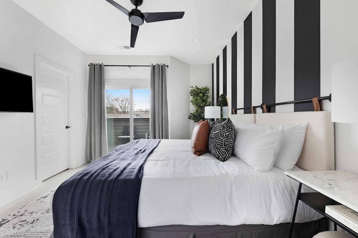 Comfortable bedroom featuring a king bed, walk-in closet, and an en-suite bathroom with a shower/tub combo, accessible from both the bedroom and kitchen.