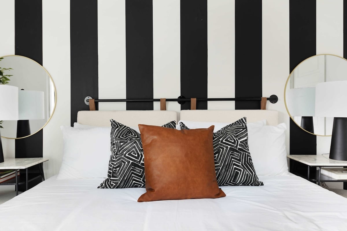 Comfortable bedroom featuring a king bed, walk-in closet, and an en-suite bathroom with a shower/tub combo, accessible from both the bedroom and kitchen.