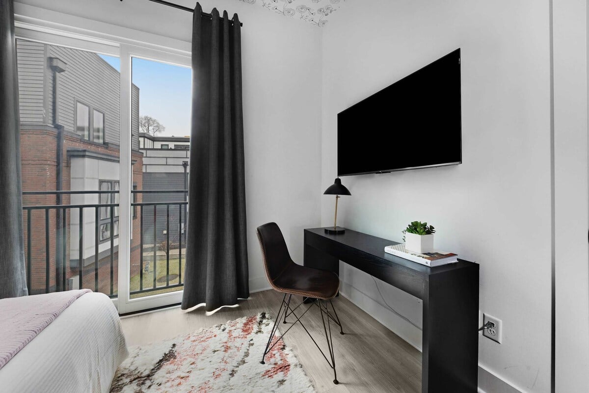 Elegant bedroom with a king bed, walk-in closet, and a private balcony featuring two chairs. The en-suite bathroom includes a modern shower for your comfort.