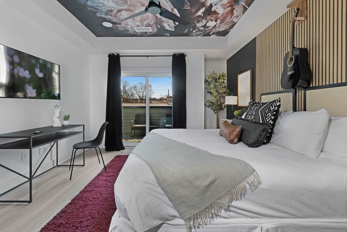 Serene bedroom with a king bed, walk-in closet, and a private balcony with two chairs. The en-suite bathroom features a modern shower for a refreshing experience.