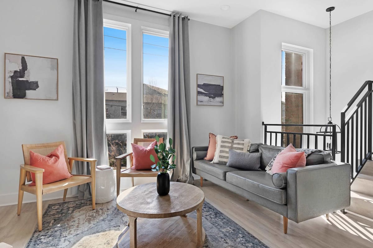 Stylish living room featuring a wall-mounted smart TV, a sleek leather couch, a modern coffee table, and three elegant accent chairs for a cozy and inviting ambiance.