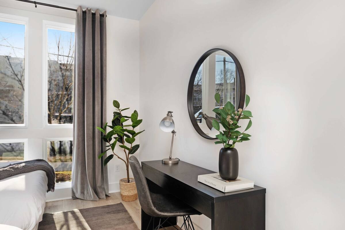 Elegant bedroom featuring a king bed, walk-in closet, and a private balcony with two chairs. Includes an en-suite bathroom with a sleek shower.