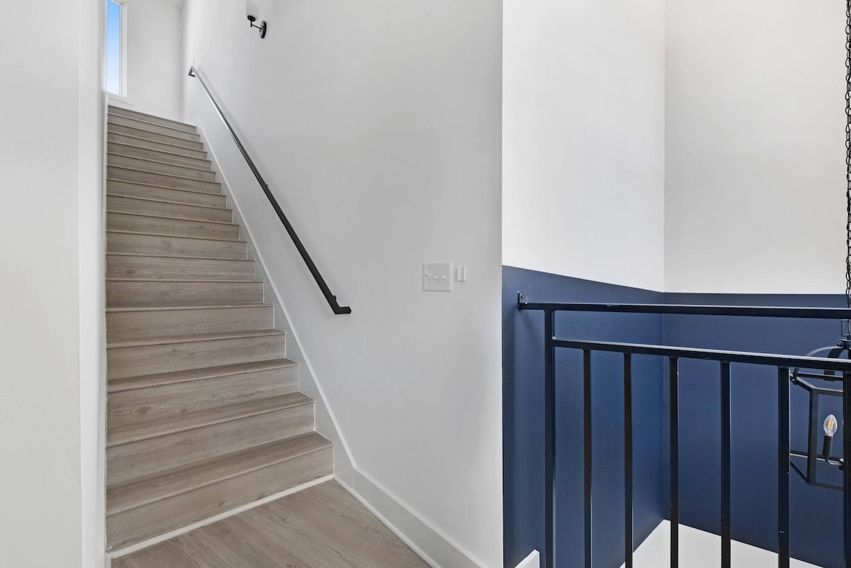 Stylish staircase with sleek blue railing and natural light.