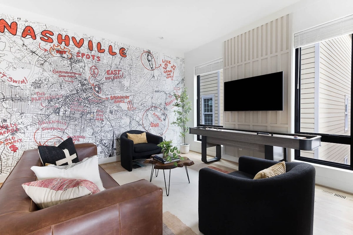 The Banjo - Spacious living room with seating, fun wallpaper, smart television, and shuffleboard.