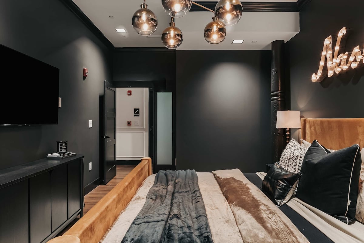The Highball - The king bedroom features bold pops of color set against dark, smoky hues, creating a rich and dramatic atmosphere.