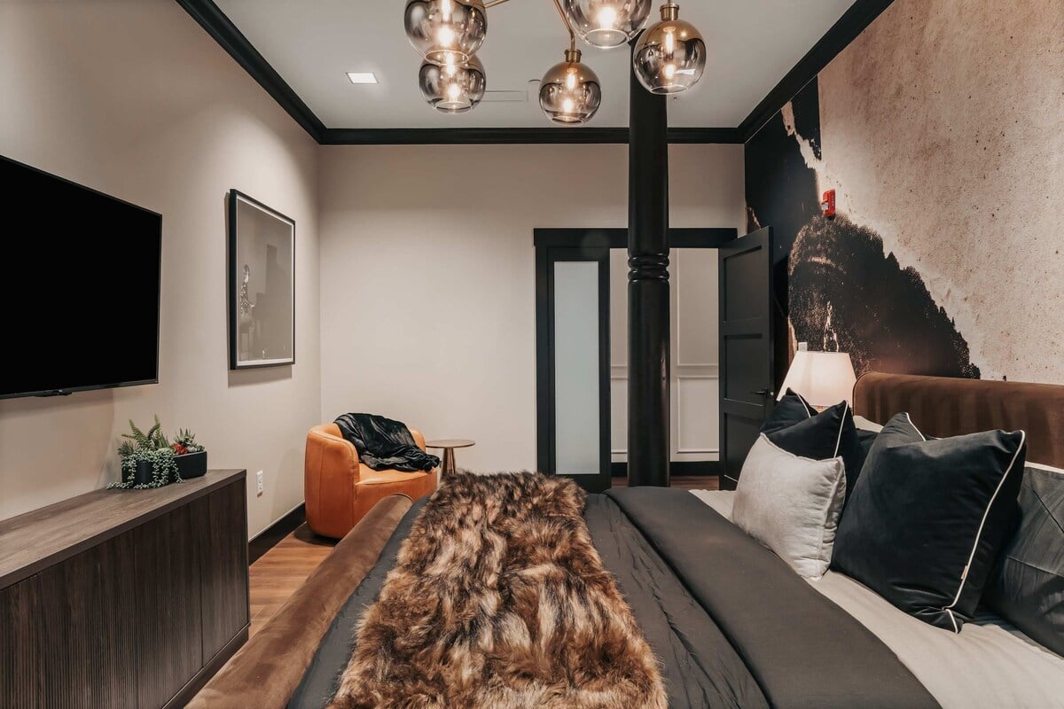 The Highball - The bedroom features a luxurious king bed, a wall-mounted smart TV, and bold design elements that create a stylish and comfortable retreat.