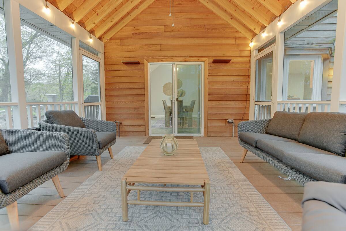 Comfy seating and cozy string lights surround the outdoor screened in porch.